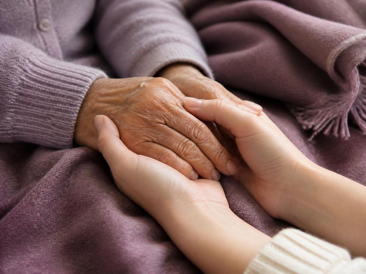 Geriatric care manager providing compassionate support Geriatric care manager holding an older client's hand during a care coordination visit